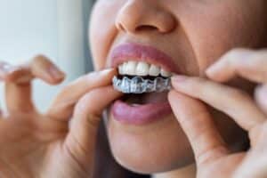 Smiling Houston woman inserts Invisalign® tray